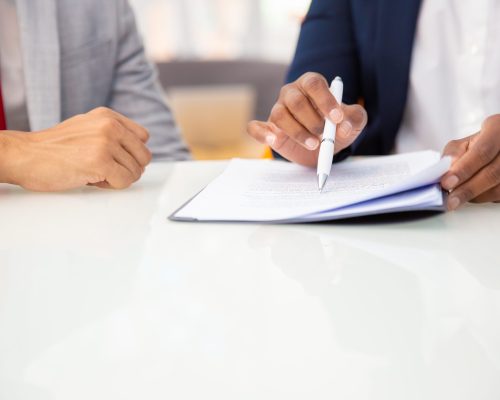 Cropped shot of business people reading contract Cropped shot of business people reading contract. Close-up partial view of professional business colleagues working with papers in office. Paperwork concept